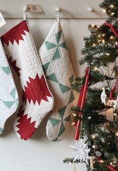 three christmas stockings hanging on the wall next to a tree