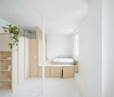 an empty room with a bed and shelves on the wall in front of it,