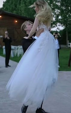 a woman in a white dress is being held up by a man with blonde hair