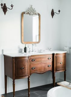 a bathroom with a sink, mirror and bathtub in the middle of the room