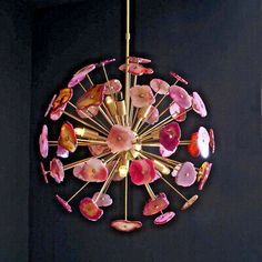 a chandelier hanging from the ceiling with pink and gold decorations on it's sides