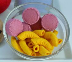 a glass bowl filled with yellow and pink macaroni shells next to a cookie