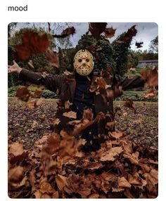 a person wearing a mask standing in leaves with their arms spread out and hands outstretched