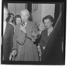 an old black and white photo of a man holding something in his mouth while surrounded by people