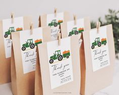 small brown bags with green and orange tractors on them are hanging from clothes pegs