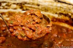 a spoon full of chili and beans in a crock pot