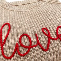 the word love is written in red yarn on a knitted sweater that says love