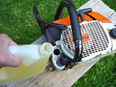 a man is using a chainsaw to cut the wood with an orange and black handle