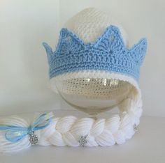 a crocheted hat with a blue crown sits next to a ball of yarn