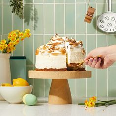 a person is decorating a cake with yellow flowers and greenery on the counter