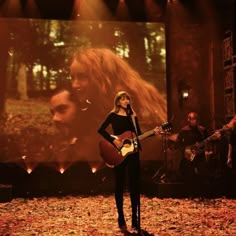 a woman standing on top of a stage holding a guitar