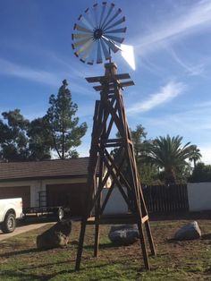 a wooden windmill sitting in the middle of a yard