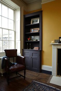 a living room with a chair, fireplace and bookshelf next to a window