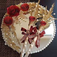 a heart shaped cake decorated with red roses and gold leafy decorations on a table