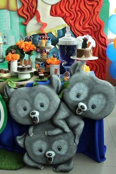 two stuffed animals sitting on top of a table next to a cake and cupcakes