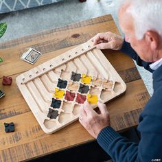 an older man is playing a board game on a wooden table with pieces of wood