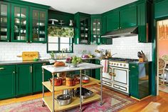 a kitchen with green cabinets and an island in front of the stove top is filled with pots and pans