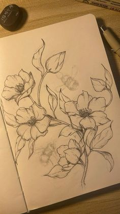 a pencil drawing of flowers on paper next to a pen and ink pad with writing