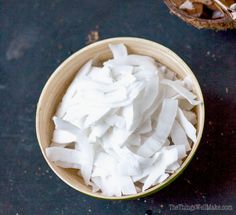 a wooden bowl filled with chopped white onions on top of a table next to a spoon