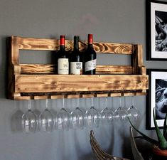 wine glasses and bottles are hanging on a wooden rack with wine glasses in front of them