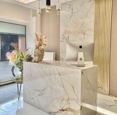 an office lobby with marble counter top and flowers on the desk in front of it