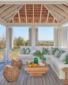 a covered porch with wicker furniture and large plants on the table in front of it