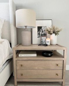 a nightstand with a lamp and pictures on it