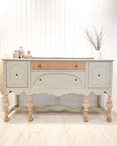 a white and wood table with drawers on it's sides, in front of a white wall