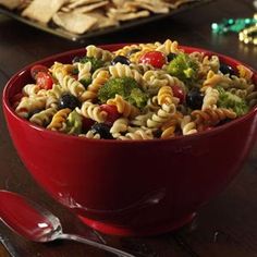 a red bowl filled with pasta salad next to crackers