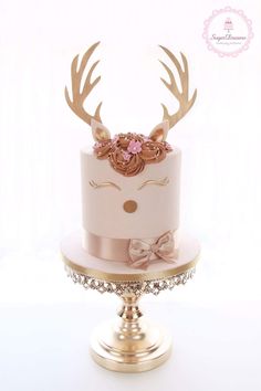 a white and pink cake with gold antlers on top