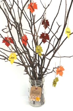 a vase filled with branches covered in fall leaves and a tag hanging from it's side