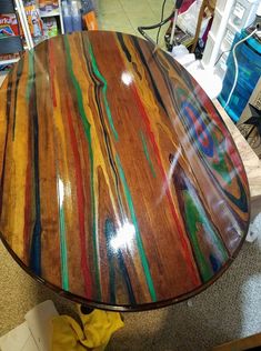 a wooden table with multicolored paint on it in a storeroom next to bookshelves