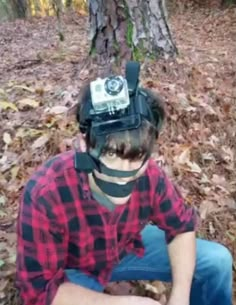 a man sitting on the ground wearing a hat with a camera attached to his head