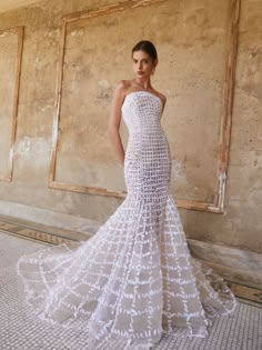 a woman in a white wedding dress standing next to a wall