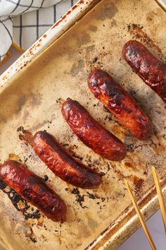 four sausages on a baking sheet with toothpicks