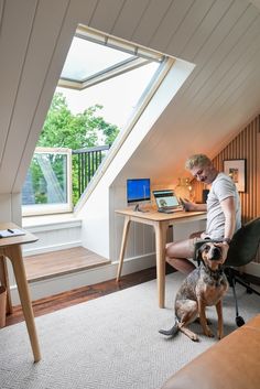 a man sitting at a desk with his dog in front of him on the floor