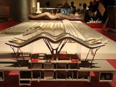 a model of a train station on display in a museum with people looking at it