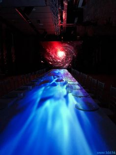 a long table is lit up with blue light in the center and chairs on either side