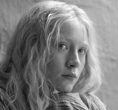 a black and white photo of a woman with long blonde hair looking at the camera