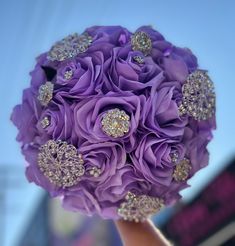 a bridal bouquet with purple flowers and jewels