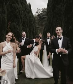 a group of people standing around each other in formal wear and tuxedo's