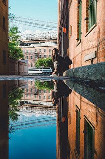 a man standing on the side of a building next to a body of water with buildings in the background