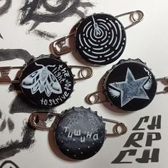 four badges with writing on them sitting on top of a piece of paper next to each other