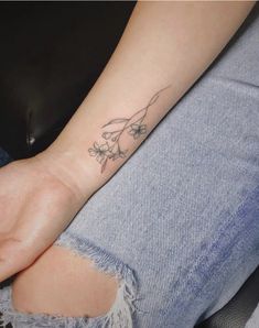 a woman's arm with a small tattoo on her left wrist and flowers in the middle