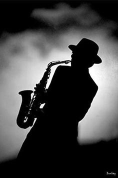 a black and white photo of a man with a saxophone in his hand, against a dark background