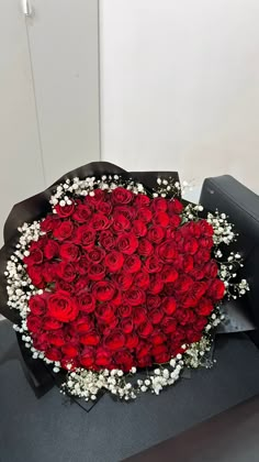 a large bouquet of red roses in a black box