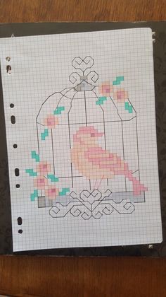 a piece of paper with a bird in a cage cross stitch pattern on top of it