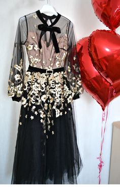 a dress and balloons are on display in front of a wall with red heart balloons