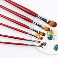 six paint brushes sitting on top of a white plate