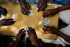 several people are playing with white squares on a wooden board in the middle of their hands